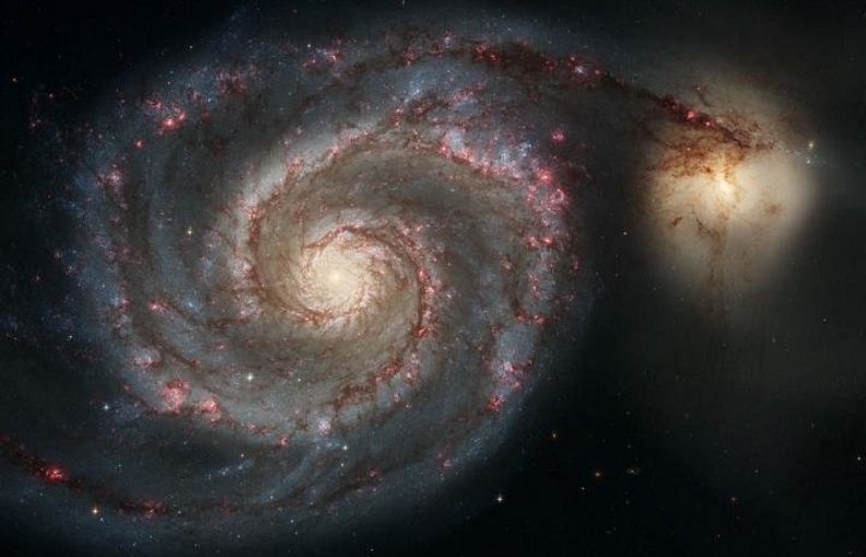 The Whirlpool Galaxy (M51a) and companion galaxy (M51b). This Hubble Space Telescope image represents a merger between two galaxies similar in mass to the Milky Way and the Large Magellanic Cloud.